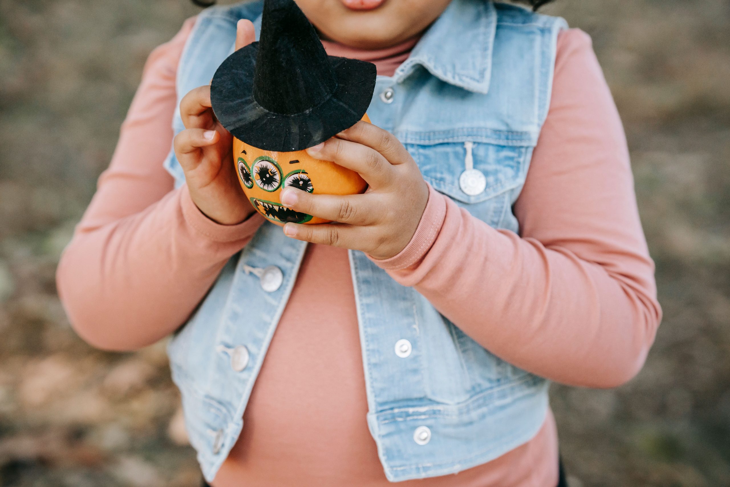 Child holding a decorated pumpkin during a fall activity, related to family preparation and ABA therapy in Houston.